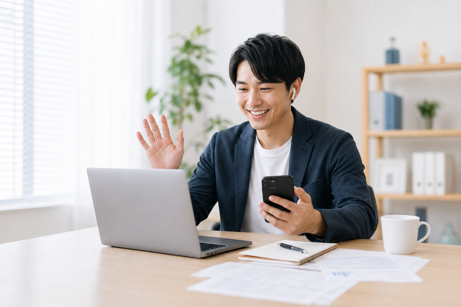 パソコンとスマートフォンでウェブ会議をする若手事業主